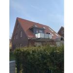 Haus mit rotem Dach, Balkon und grüner Hecke