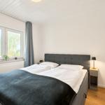Schlafzimmer mit Doppelbett, Fenster und Nachttisch.