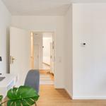 Helle Wohnung mit Arbeitsplatz, Pflanze und Bildern an der Wand.