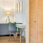 Ein Raum mit Schreibtisch, Stuhl und Sofa. Holztür und Wanddekoration sind sichtbar.