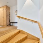 Holzgetäfelte Treppe mit Handlauf führt in ein Zimmer mit Holzschrank und Kleiderständer.