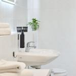 Badezimmer mit Waschbecken, Handtuch und Pflanze.