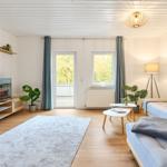 Wohnzimmer mit Sofa, Fernseher und Fenster zur Terrasse.