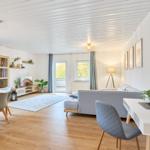 Wohnzimmer mit Essbereich, Sofa, Schreibtisch und Balkonzugang.