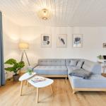 Wohnzimmer mit grauem Sofa, Holzboden und Fenster mit Blick auf Grün.