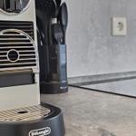 Espresso-Maschine auf Küchenarbeitsfläche mit Kochutensilien im Hintergrund.