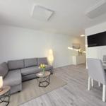 Wohn- und Essbereich mit Sofa, Esstisch und Fernseher.