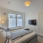 Schlafzimmer mit Doppelbett, TV und Kleiderschrank. Fenster mit Jalousien.