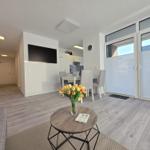 Wohnzimmer mit Essbereich, TV und Balkon. Holzboden und modern eingerichtet.