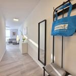 Flur mit Spiegel, blauer Tasche und Blick ins Wohnzimmer.