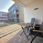 Terrasse mit Tisch und Stühlen, Blick auf Wohngebäude und Garten.