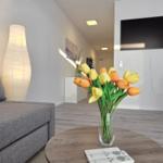 Ein Wohnzimmer mit Sofa, Fernseher und Tulpen im Vordergrund.