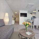 Wohnzimmer mit Sofa, Esstisch und Fernseher. Blumen auf Tisch.