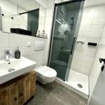 Badezimmer mit Dusche, Waschbecken und Toilette.