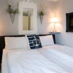 Bedroom with bed, nightstand, mirror, and wall-mounted fireplace.