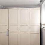 Bedroom with white wardrobe and window with sailboat model.