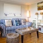 Living room with sofa, coffee table, and cabinet. Wall art and lighting visible.
