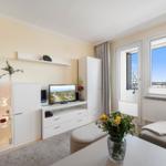 Wohnzimmer mit Fernseher, Glasvitrine und Blick auf die Stadt