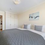 Schlafzimmer mit Bett, Kleiderschrank und Wandbild.