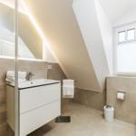 Badezimmer mit Dusche, Waschbecken und Toilette unter Dachschrägen.