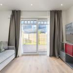 Wohnzimmer mit Sofa, Fernseher und Blick auf den Garten.