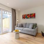 Wohnzimmer mit Sofa, Tisch und Glasfront zur Terrasse.