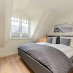 Schlafzimmer mit Dachschrägen, Bett, Fenster und Fernseher.