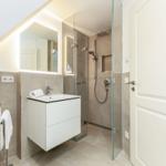 Badezimmer mit Dusche, Waschbecken und Spiegel