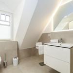 Badezimmer mit Dusche, Waschbecken und Toilette unter Dachschrägen.