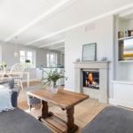 Wohnzimmer mit Kamin, TV und Essbereich. Holzboden und weiße Wände.