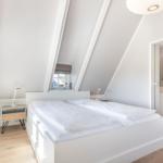 Schlafzimmer mit Doppelbett, Holzboden und Dachschrägen. Badezimmer im Anschluss.