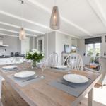 Essbereich mit Holztisch, Stühlen und Küche im Hintergrund.