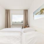 Schlafzimmer mit Doppelbett, Fenster und Wandbild.