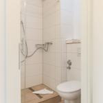 Dusche mit Glaswand, Toilette und Handtuch