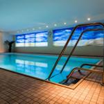 Innenpool mit Metalltreppe und großen Fenstern mit Meerblicksimulation.