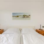 Schlafzimmer mit Doppelbett, zwei Nachttischen und Wandbild