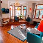 Wohnzimmer mit Holzboden, Sofa, Stühlen und Fenstern.