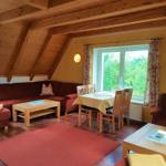 Wohn- und Essbereich mit Holzdecke, rotem Sofa und Tisch mit Stühlen.