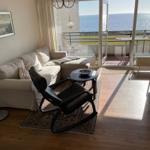 Wohnzimmer mit Sofa, Sessel und Blick aufs Meer.