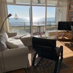 Wohnzimmer mit Blick auf das Meer und Balkon mit Tisch.