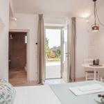 Bedroom with view to balcony, small table, and bathroom in background.