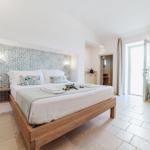 Bedroom with wooden bed, mosaic wall, and terrace door.