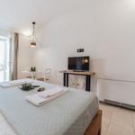 Bedroom with bed, TV, and table with chairs. Window with view outside.
