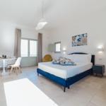 Schlafzimmer mit Bett, Esstisch und Fenster. Wandbild und Nachttisch sind sichtbar.