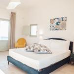 Schlafzimmer mit Bett, Nachttisch, Stuhl und Fenster.