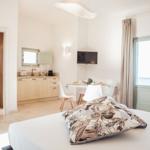 Schlafzimmer mit kleiner Küche, Essplatz und Bad im Hintergrund.