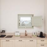 Küche mit Arbeitsplatte, Spüle, Fenster und Küchengeräten.