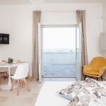 Schlafzimmer mit Blick auf Balkon und Meeresblick. Gelber Sessel, Essbereich und TV.