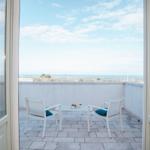 Terrasse mit zwei Stühlen und Tisch. Blick auf Meer und Landschaft.