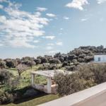 Weißes Haus in Olivenhain unter blauem Himmel mit Blick auf Hügel.